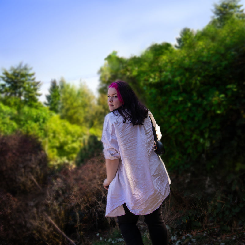 Canadian hairstylist Reese Hobbs holding a hairdryer over her shoulder with a blurred natural background. Sugarloaf Mountain Hairstylist Reese Hobbs Nanaimo - Multinex Media-Photoshoot